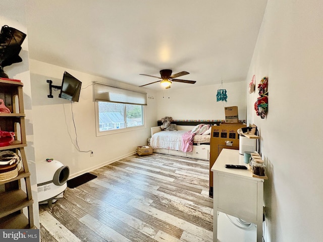 bedroom featuring baseboards, wood finished floors, and a ceiling fan