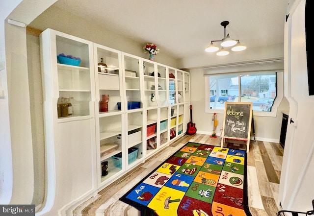 recreation room featuring baseboards and wood finished floors