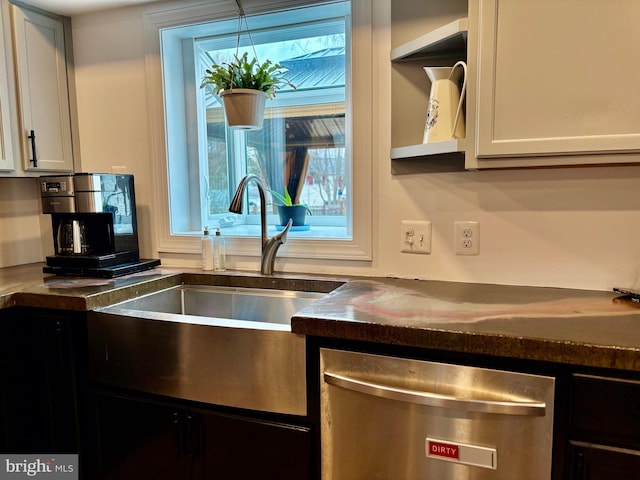 kitchen with stainless steel dishwasher, dark countertops, white cabinetry, and a sink