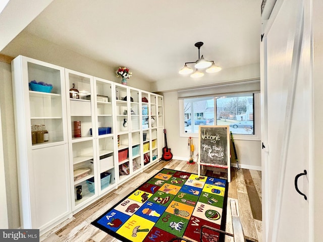 recreation room with baseboards and wood finished floors