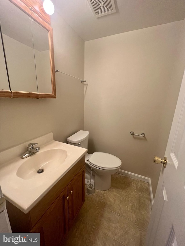 bathroom featuring vanity, baseboards, visible vents, tile patterned floors, and toilet