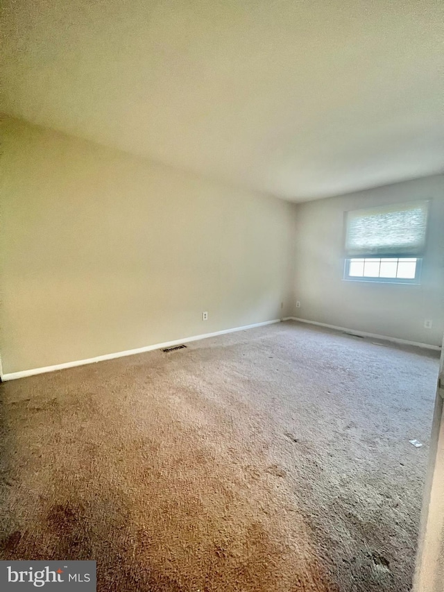 spare room with carpet flooring, baseboards, and visible vents