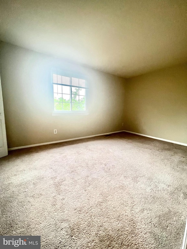 carpeted spare room featuring baseboards