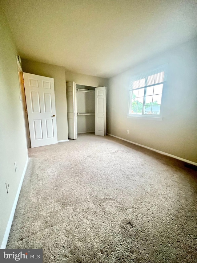 unfurnished bedroom with carpet, a closet, and baseboards