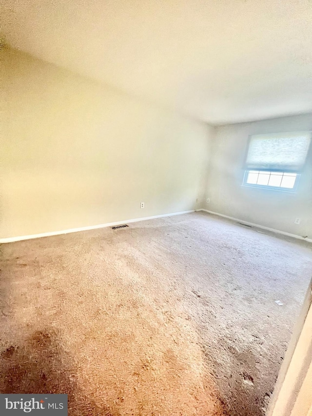 empty room featuring baseboards, visible vents, and carpet floors