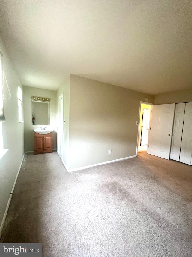 unfurnished bedroom featuring baseboards, carpet floors, and a sink