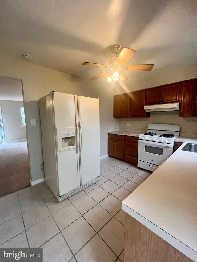 kitchen featuring under cabinet range hood, light tile patterned floors, white appliances, and light countertops