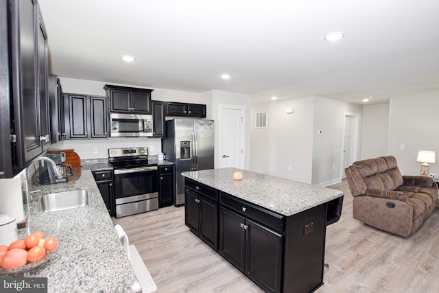 kitchen featuring visible vents, open floor plan, dark cabinets, stainless steel appliances, and a sink