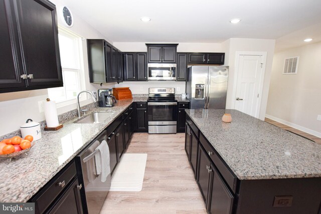 kitchen featuring visible vents, a sink, a center island, stainless steel appliances, and light wood finished floors