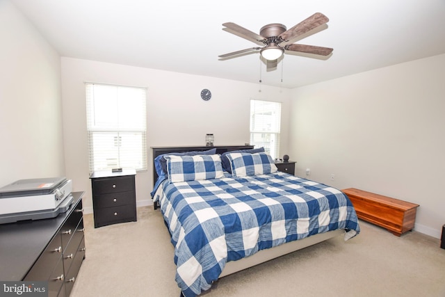 bedroom with multiple windows, a ceiling fan, baseboards, and light carpet