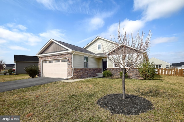 view of front of property featuring aphalt driveway, stone siding, fence, a front yard, and an attached garage