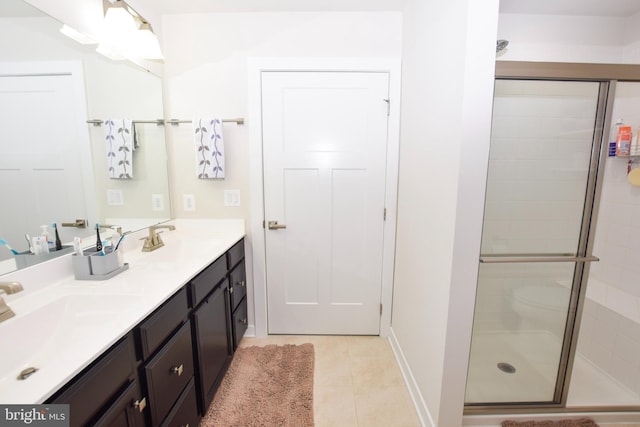 bathroom featuring tile patterned flooring, a shower stall, double vanity, and a sink