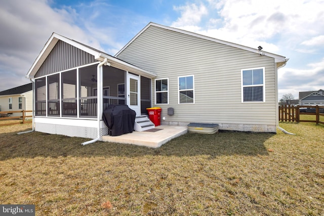 rear view of property featuring a patio area, fence, a lawn, and a sunroom