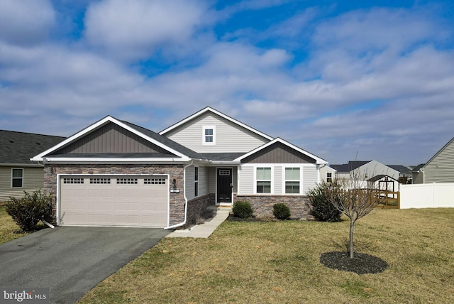 view of front of property with a front yard, fence, driveway, a garage, and stone siding