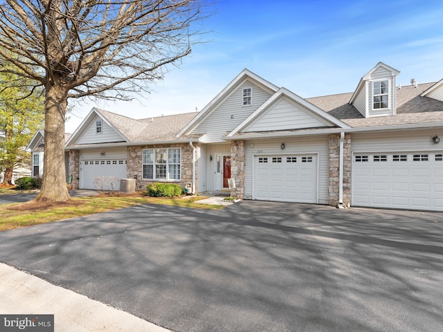 view of front of house with aphalt driveway, stone siding, an attached garage, and a shingled roof