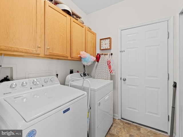 laundry room featuring cabinet space, stone finish floor, and separate washer and dryer