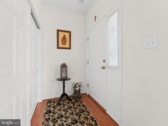 foyer featuring visible vents, baseboards, and wood finished floors