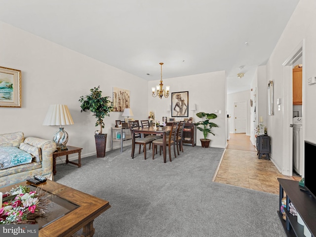 living room featuring light carpet, a chandelier, washer / dryer, and baseboards