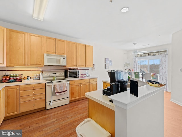 kitchen with light wood-style flooring, light brown cabinetry, a center island, white appliances, and light countertops