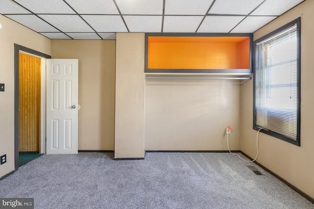 unfurnished bedroom with visible vents, a paneled ceiling, and carpet