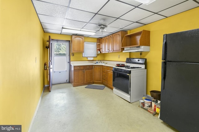 kitchen with open shelves, freestanding refrigerator, light countertops, under cabinet range hood, and range with gas cooktop