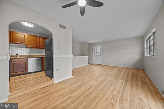 interior space with visible vents, ceiling fan, freestanding refrigerator, brown cabinetry, and stainless steel dishwasher