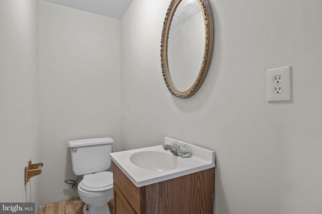 half bath featuring toilet, wood finished floors, and vanity