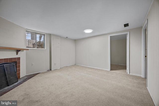 unfurnished living room with carpet, baseboards, and a tile fireplace