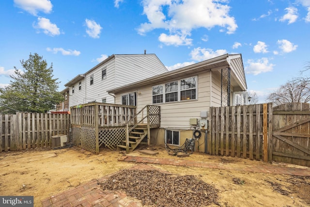 back of house with central air condition unit, a wooden deck, a fenced backyard, and a gate