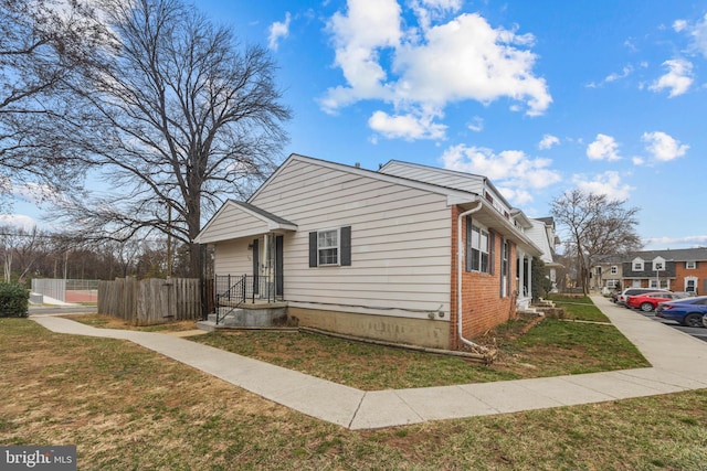 view of front of house with a front lawn, fence, and brick siding