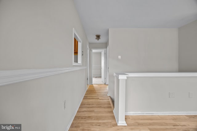 corridor with baseboards and light wood-style flooring