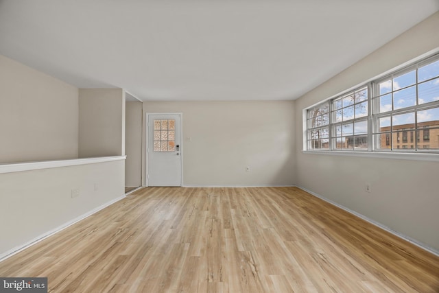 spare room with baseboards and wood finished floors