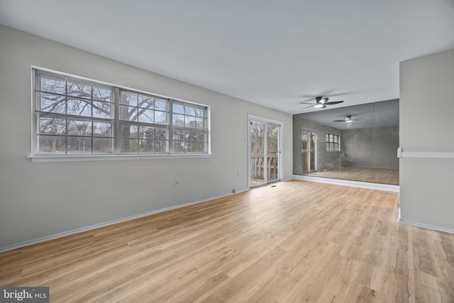 unfurnished living room featuring wood finished floors, baseboards, and ceiling fan