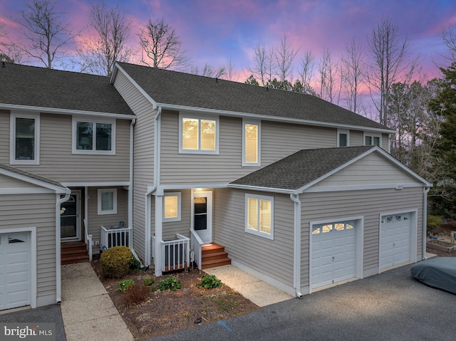 view of front of home with a garage, driveway, and a shingled roof