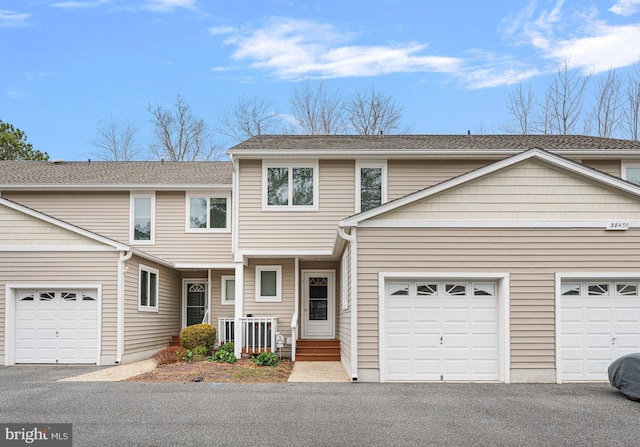 multi unit property featuring aphalt driveway, an attached garage, and a porch