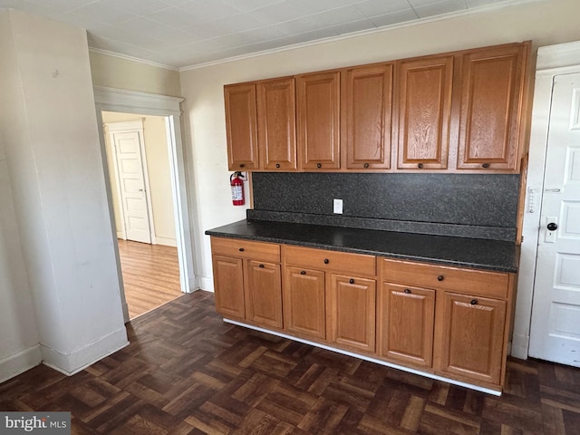 kitchen featuring dark countertops, brown cabinetry, tasteful backsplash, and baseboards