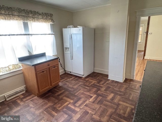 kitchen with dark countertops, visible vents, baseboards, white refrigerator with ice dispenser, and crown molding