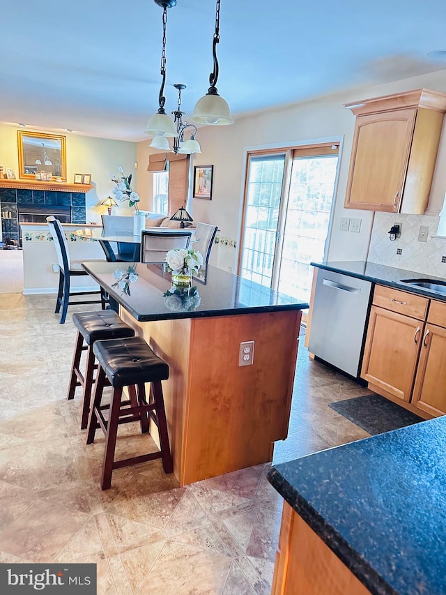 kitchen featuring light brown cabinets, a kitchen island, backsplash, dishwasher, and a kitchen bar