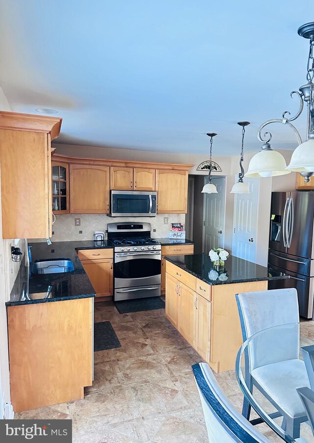 kitchen featuring a sink, tasteful backsplash, a kitchen island, appliances with stainless steel finishes, and glass insert cabinets