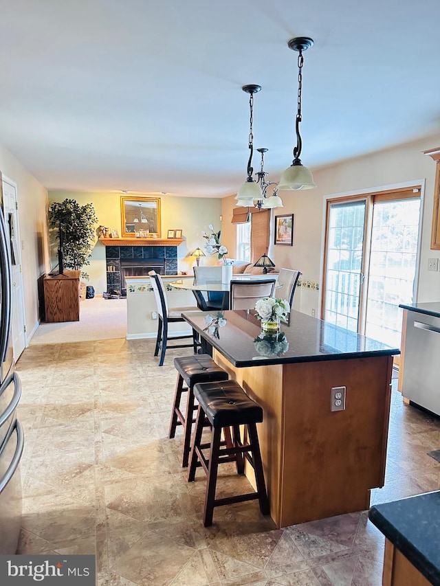 kitchen with pendant lighting, dishwasher, dark countertops, a kitchen breakfast bar, and a center island