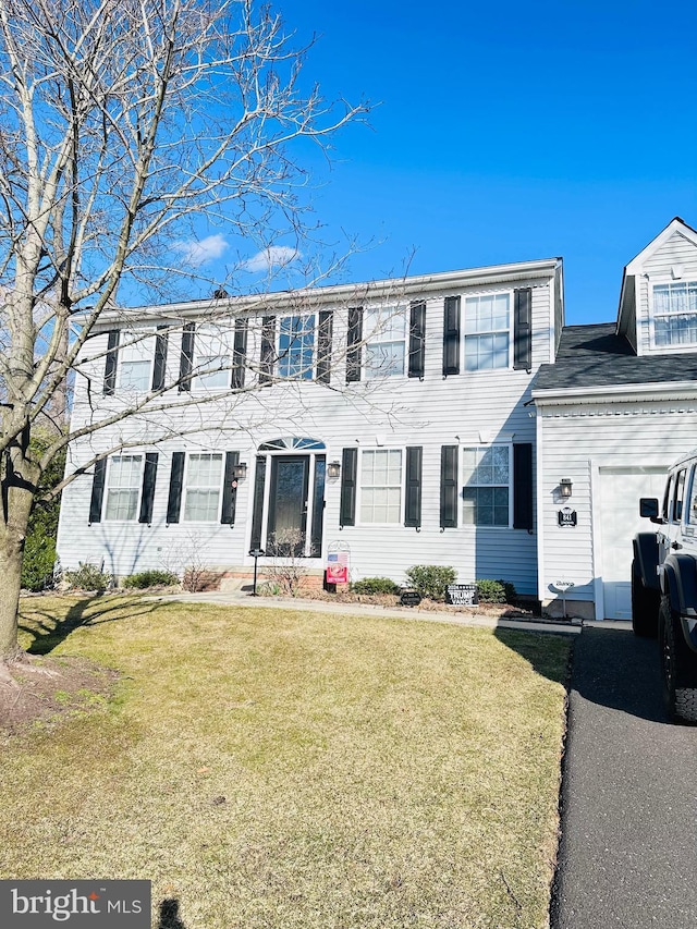 colonial inspired home featuring an attached garage, driveway, and a front yard