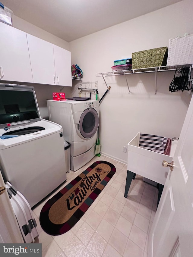 laundry room with light tile patterned floors, cabinet space, baseboards, and washer and clothes dryer