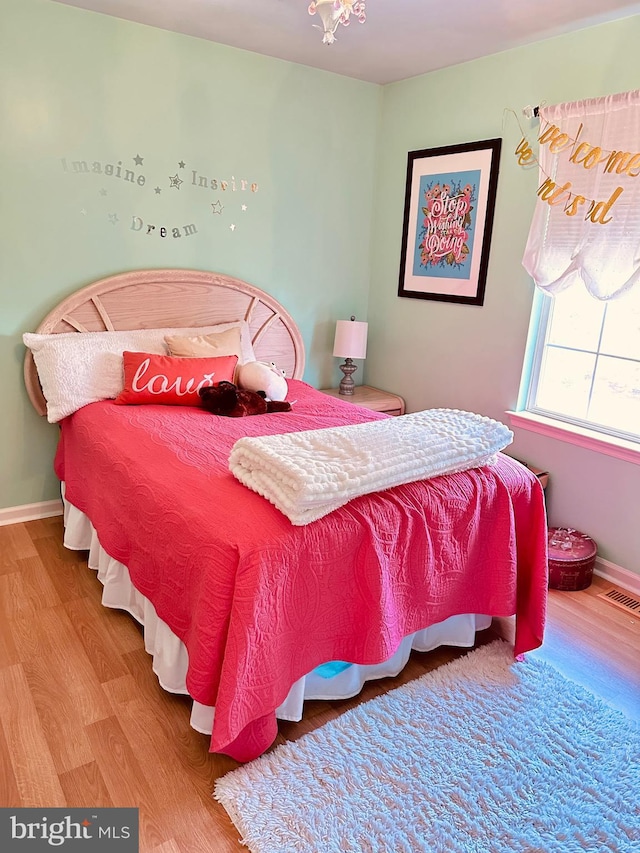 bedroom featuring wood finished floors, visible vents, and baseboards