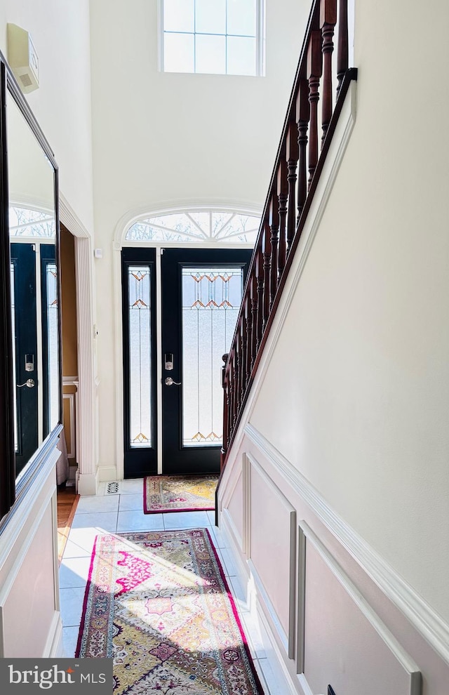 foyer entrance featuring stairs, a high ceiling, and light tile patterned floors