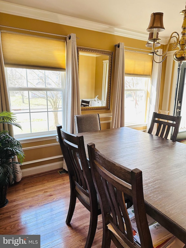 dining space featuring baseboards, an inviting chandelier, ornamental molding, and hardwood / wood-style flooring