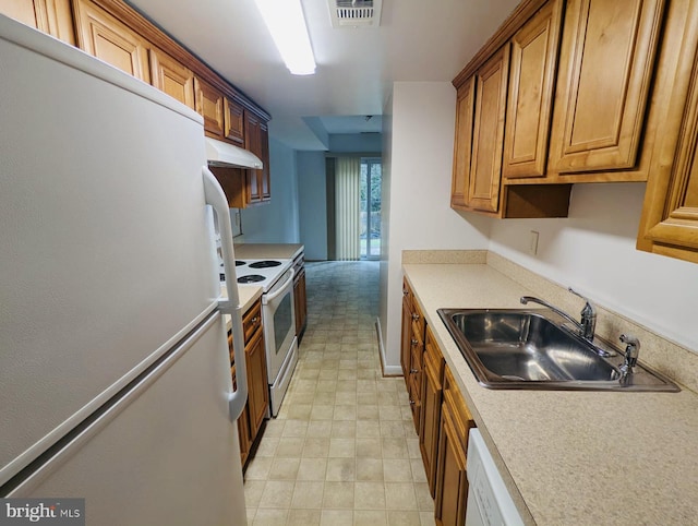 kitchen with visible vents, a sink, under cabinet range hood, white appliances, and brown cabinetry