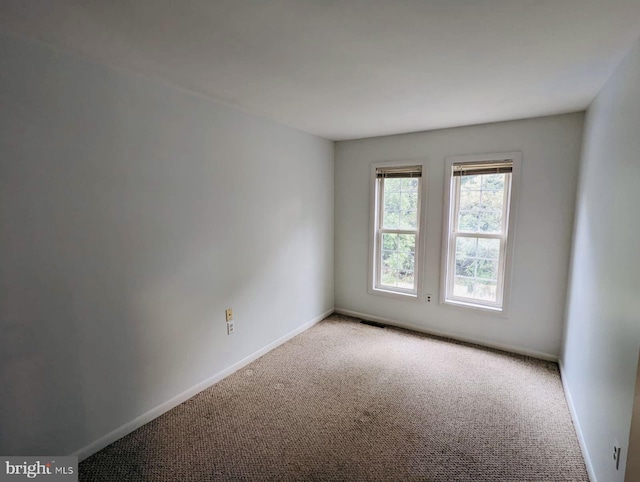 carpeted empty room featuring visible vents and baseboards