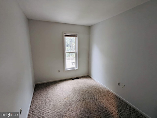 empty room featuring carpet, visible vents, and baseboards