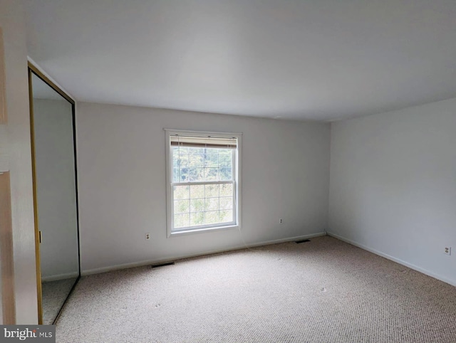 unfurnished bedroom featuring carpet flooring, baseboards, visible vents, and a closet