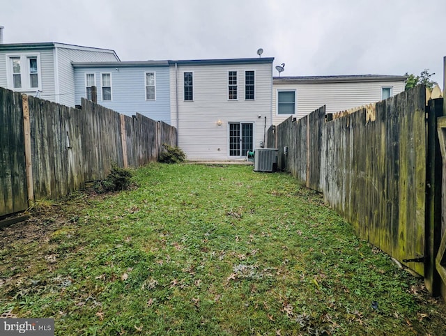 rear view of house featuring central air condition unit, a lawn, and a fenced backyard